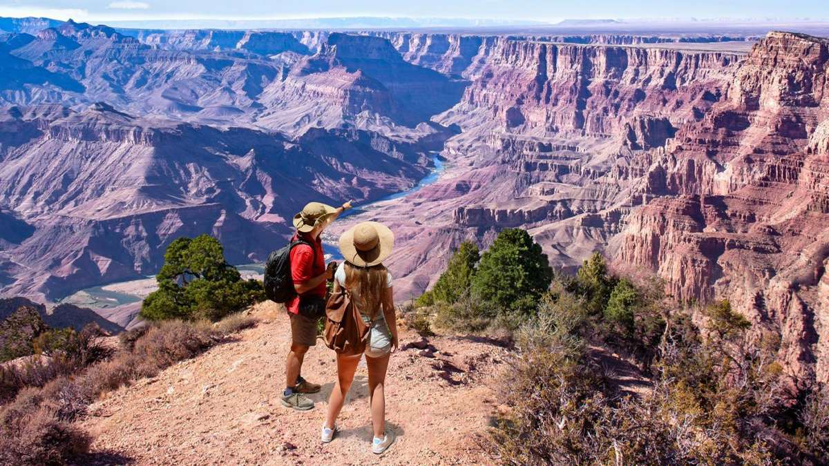 man and woman hiking through the grand canyon national park pointing in the distance in Arizona, USA